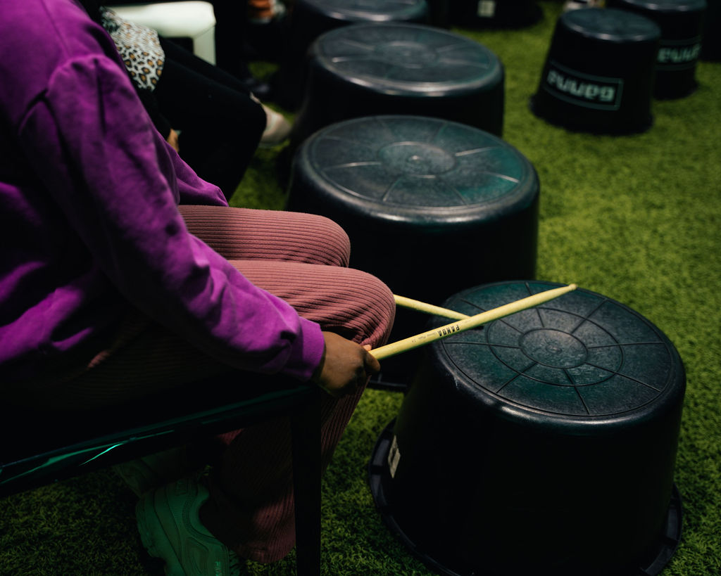 Kind slaat met drumstokken op een omgekeerde emmer.